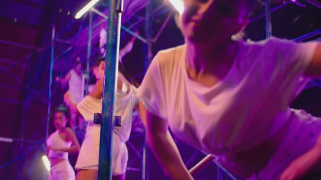 Many female dancers dressed in white shorts dancing inside abandoned building in high multistage  construction . Stylish Girls dancing, twerking , doing gymnastic movements , jumping . 
