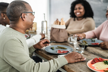 Happy afro Latin family eating healthy lunch with fresh vegetables at home - Food and parents unity concept
