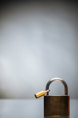 Fototapeta premium Gold iron lock placed on black reflexive glass on black background with tiny lock on it. 