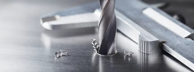Foto op Aluminium metal drill bit make holes in steel billet on industrial drilling machine. Metal work industry. multi cutting tool and end mill. © evkaz