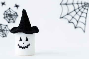 Halloween concept - scary face of candle in black hat on a gray holiday background	
