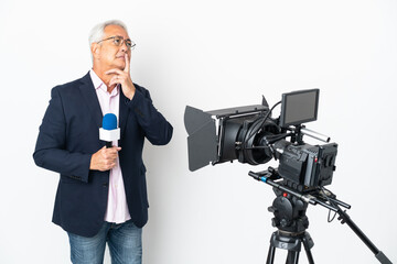 Reporter Middle age Brazilian man holding a microphone and reporting news isolated on white background having doubts while looking up