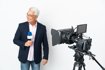 Reporter Middle age Brazilian man holding a microphone and reporting news isolated on white background looking to the side and smiling