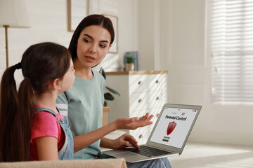 Mother installing parental control app on laptop to ensure her child's safety at home