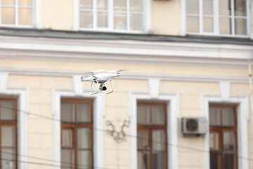 Flight of drone on background of city. Quadcopter collects materials from scene of accident or...