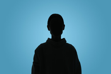 Silhouette of anonymous woman on light blue background
