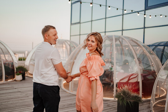 a man and a woman in love walk to a rooftop cafe on a date.