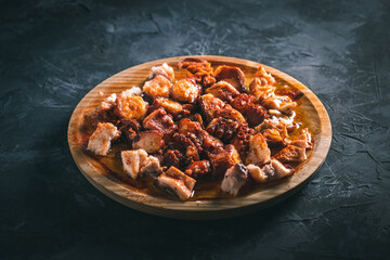 “Pulpo a la gallega”. Plate of chopped octopus with oil and paprika in a round wooden plate on a dark table. Typical food of Galicia, Spain. 