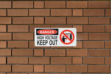 A danger high voltage warning sign on a brick wall