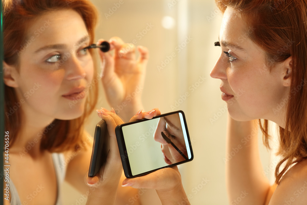 Wall mural woman putting on make up watching video tutorial