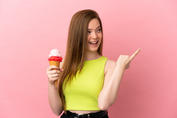 Teenager girl with a cornet ice cream over isolated pink background intending to realizes the solution while lifting a finger up