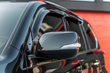 Part of the black modern car. Close-up rearview mirror. Exterior detail