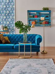 Blue classic sofa furniture home design, gold lamp and middle table, wooden palette bookshelf, vase of green plant and home accessory style,interior decor.