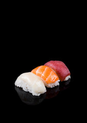 Nigiri sushi with salmon, tuna, hake on black background.