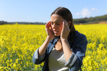 Woman suffering head ache in a field on summer