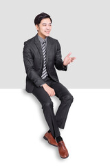 Young business man sitting on blank panel.Isolated on white background.