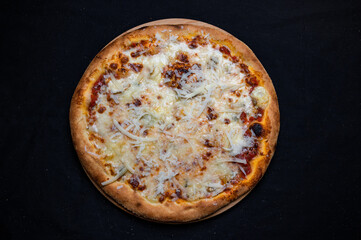 Pizza quatro formaggi with tomato sauce and 4 kinds of cheese on a black background.