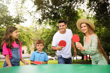 Happy family playing ping pong in park