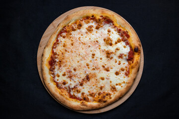 Pizza with tomato sauce and mozzarella cheese on a black background.