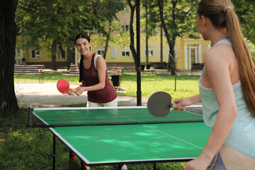 Young women playing ping pong in park