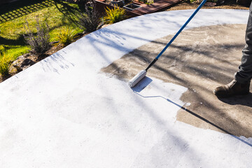 painting backyard or driveway concrete paving with paint roller, DIY and home improvement