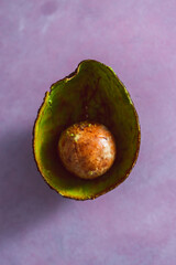 half empty avocado with pulp removed and only pip and skin remaining