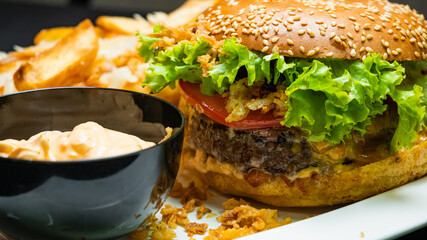Burger with beef, french fries and sauce on a gray plate
