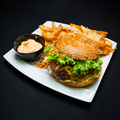 Burger with beef, french fries and sauce on a gray plate