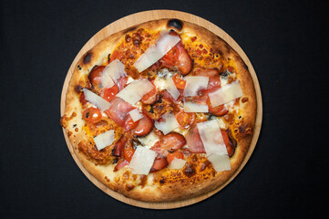 Pizza with tomato sauce, smoked pork ham, mozzarella and cherry tomatoes on black fudal