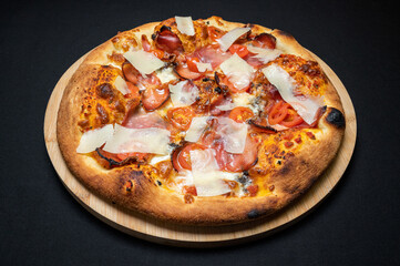 Pizza with tomato sauce, smoked pork ham, mozzarella and cherry tomatoes on black fudal