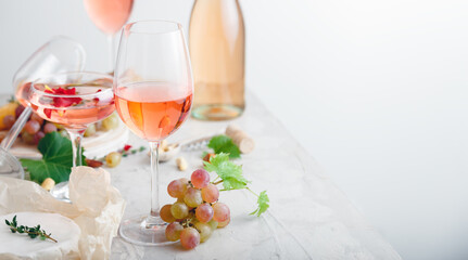 Rose wine in different wineglasses bottle on white table with grapes cheese, snacks bouquet of...