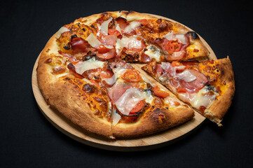 Pizza with tomato sauce, smoked pork ham, mozzarella and cherry tomatoes on black fudal