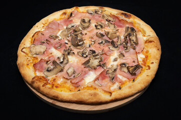 Pizza with tomato sauce, mozzarella, smoked pork ham and mushrooms on a black background.