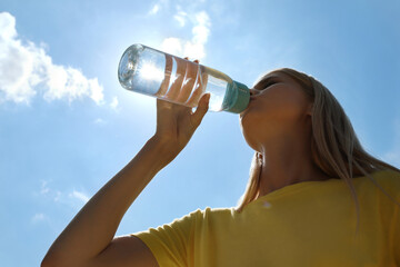 Woman drinking water to prevent heat stroke outdoors - obrazy, fototapety, plakaty