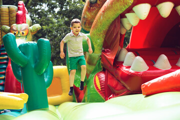 Little boy child jumping on an inflatable multi-colored slide.