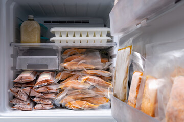 freezer of modern frigerator full with frozen food products in quarantine or work from home period...