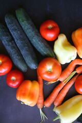 Zucchini, tomatoes, peppers, carrots and cucumbers on dark background. Flat lay.