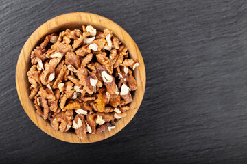 Walnut in wooden bowl on black background with copy space.