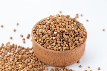 Dried buckwheat in a wooden dish on white background. Stockpiling. Buckwheat grains. Grain culture. Pandemic.