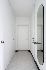 White, long corridor with modern round mirror