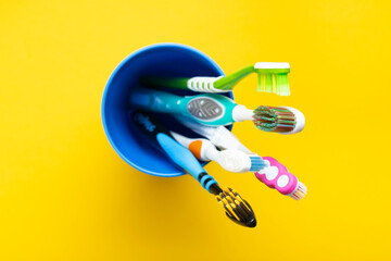 Fototapeta na wymiar Toothbrushes in a cup on a yellow background. Health care, dental hygiene. Space for text.