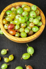 Ripe gooseberry in a wood plate, place for text,  summer harvest of berries.