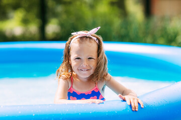 Portrait of a beautiful baby girl in the pool in the garden