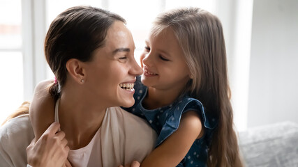 Close up of happy small Caucasian girl child hug smiling young mother feel grateful thankful. Overjoyed mom and little daughter embrace show love and care, enjoy time together. Motherhood concept.