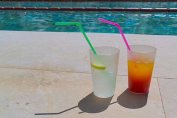 Bright cocktails with straws close-up by the pool in the hotel.