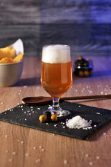 glass of beer with foam and snacks in the background. Elaboration of craft beer. Brewing