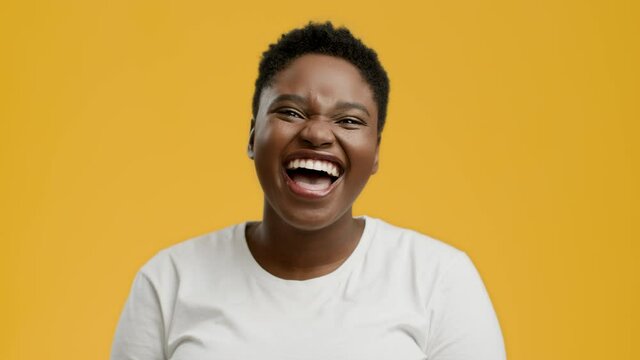 Plus-Size African American Lady Laughing Out Loud Over Yellow Background