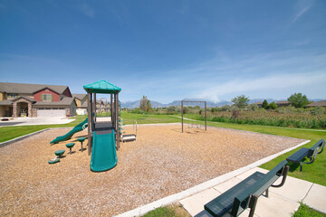 Children swings and slides at a community playground with mountain and sky view