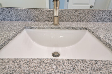 Close up of single basin undermount sink with stainless steel faucet in bathroom