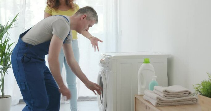 Woman showing the broken washing machine to the technician